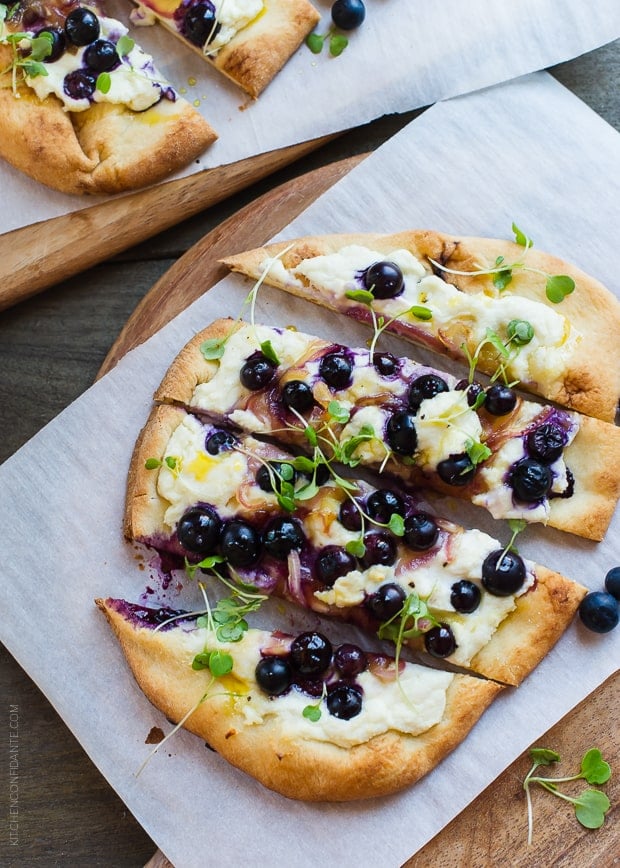 Blueberry, Feta and Honey-Caramelized Onion Naan Pizza sliced on a cutting board.