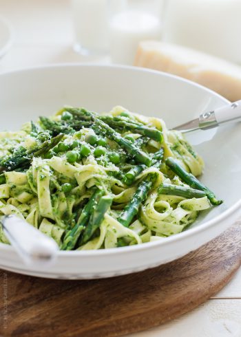 A bowl filled with Fettuccine topped with Creamy Spinach Sauce, Asparagus and Peas.