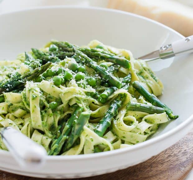 A bowl filled with Fettuccine topped with Creamy Spinach Sauce, Asparagus and Peas.