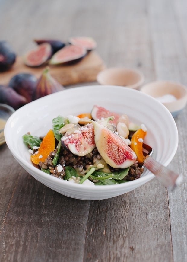 Fig and Apricot Summer Lentil Salad in a white bowl on a wooden surface.