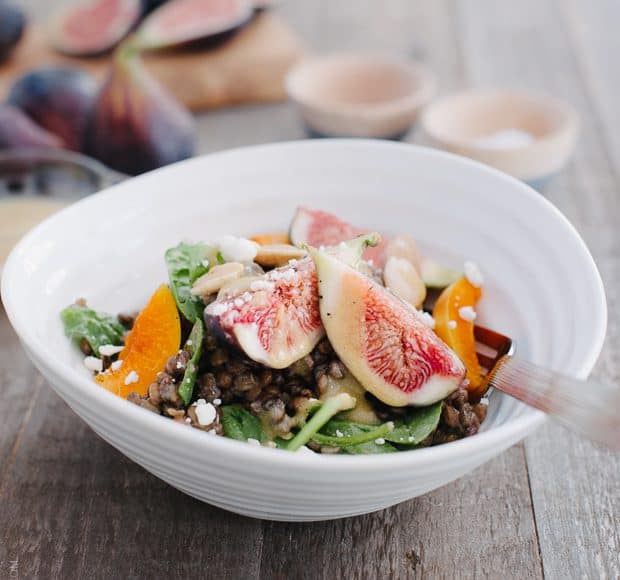 Fig and Apricot Summer Lentil Salad in a white bowl on a wooden surface.