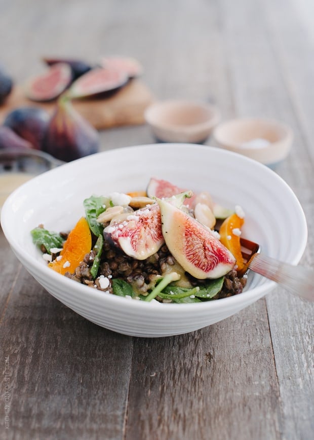 Fig and Apricot Summer Lentil Salad in a white bowl on a wooden surface.