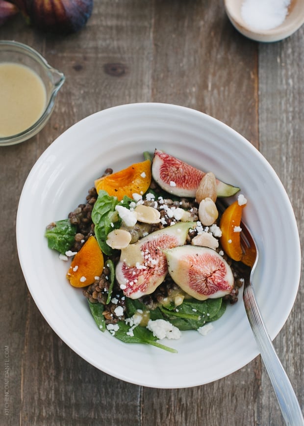 Fig and Apricot Summer Lentil Salad in a white bowl on a wooden surface.