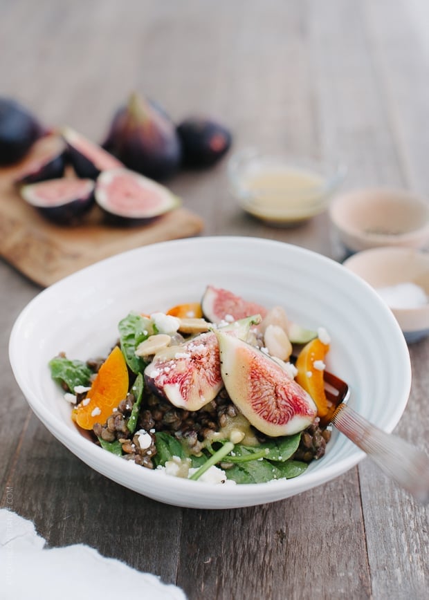 Fig and Apricot Summer Lentil Salad in a white bowl on a wooden surface.