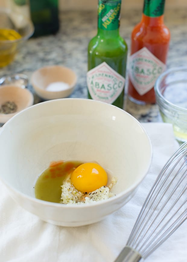 A raw egg and other ingredients in a white bowl.