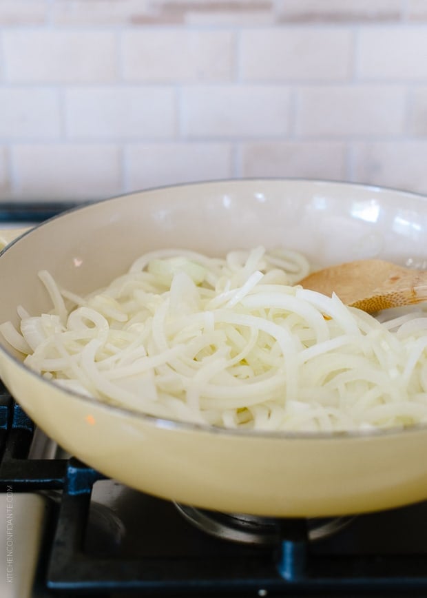 Caramelizing slices of yellow onions in a pan.