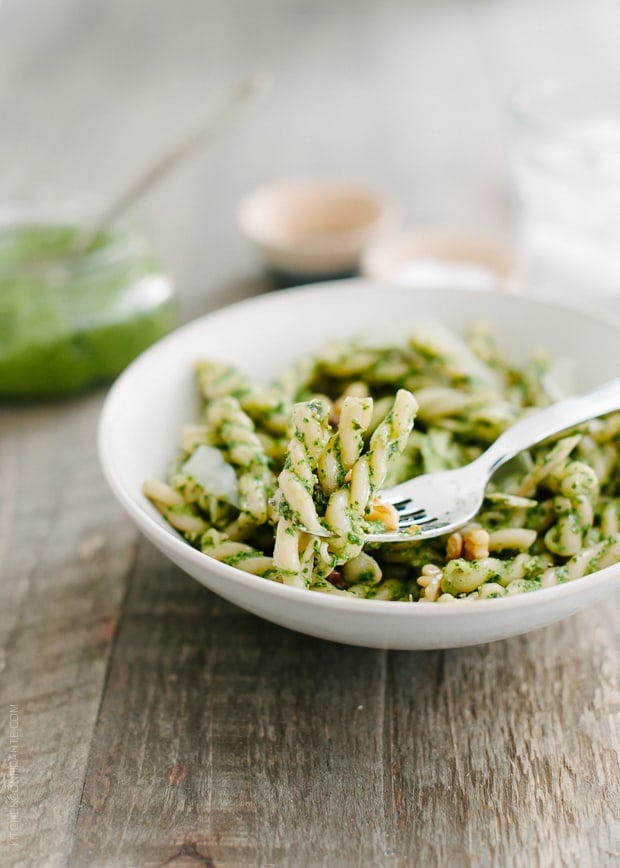 A white bowl filled with pesto pasta.