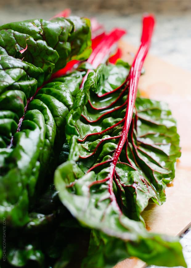 Several stalks of Swiss chard on a wooden surface.