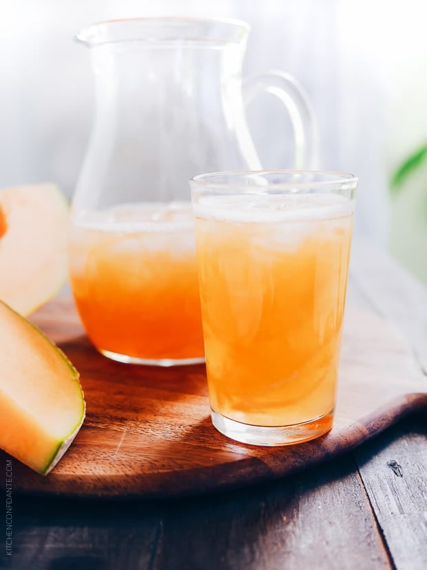 A pitcher and a glass full of icy cold cantaloupe juice.