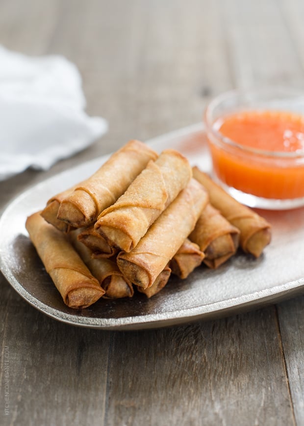 Lumpiang Shanghai - Filipino Spring Rolls (Lumpia) stacked on a platter with dipping sauce in the background