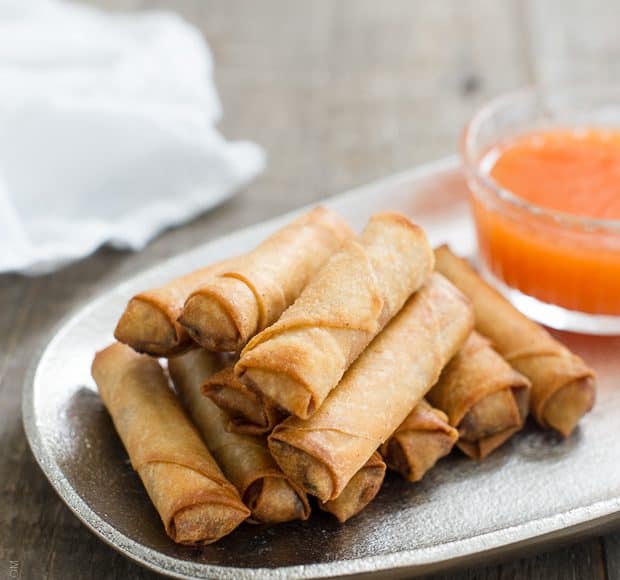 Lumpiang Shanghai - Filipino Spring Rolls (Lumpia) stacked on a platter with dipping sauce in the background
