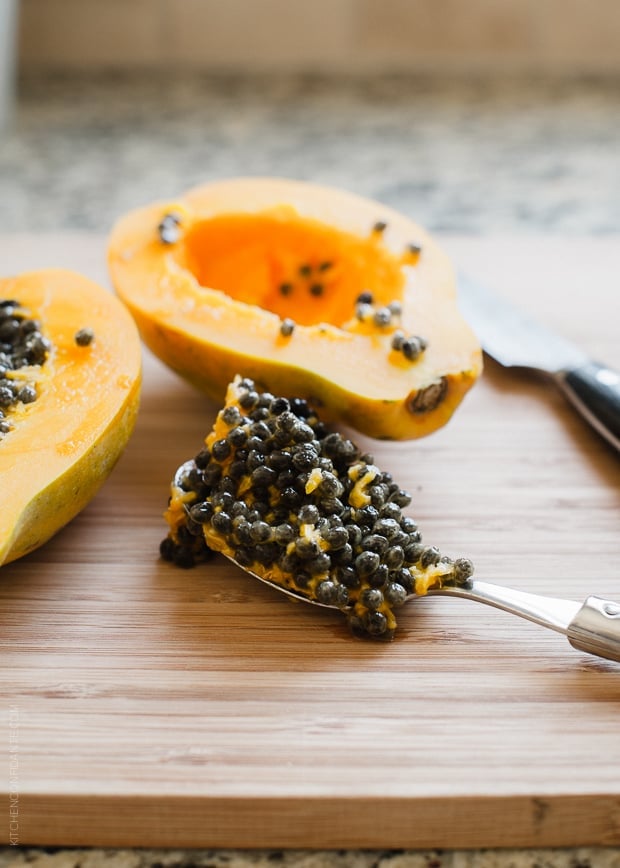 Papaya seeds scooped out onto a wooden cutting board.