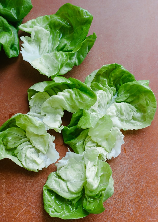 Butter lettuce leaves on a cutting board.