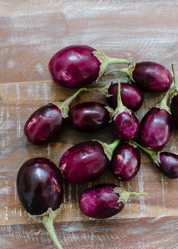 A variety of Indian eggplants on a wooden surface.