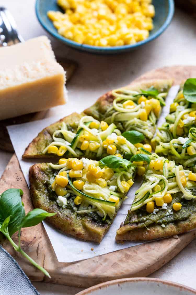 Zucchini, Corn and Pesto Flatbreads sliced on a wooden board.