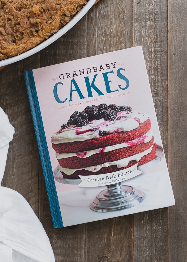 Grandbaby Cakes cookbook on a rustic surface with a sweet potato coffee cake in the background.