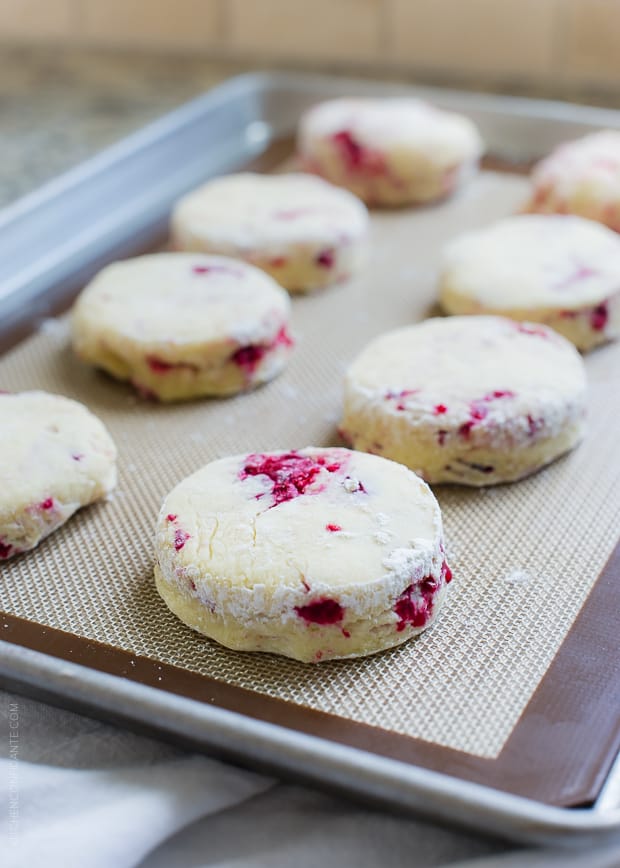 unbaked coconut raspberry scones on a rimmed baking sheet and silicone baking mat