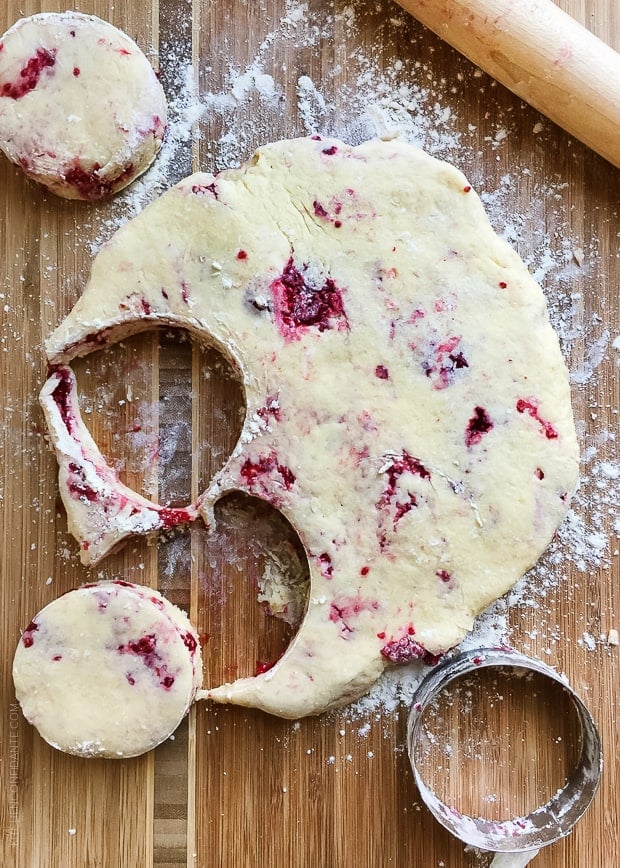 coconut raspberry scone dough with biscuit cutter and rolling bin on wooden board