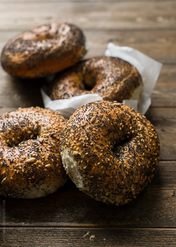 Four bagels arranged on a wooden surface.