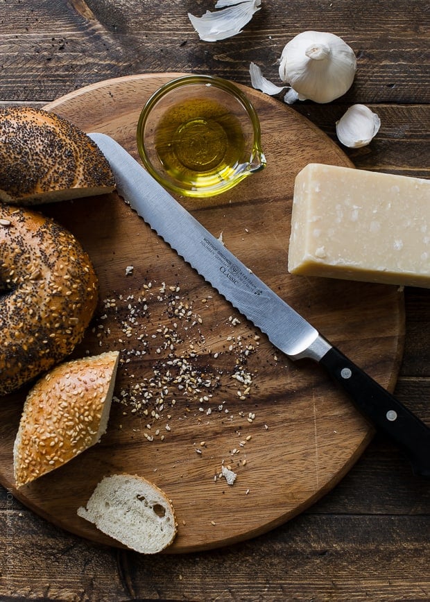 Sliced bagels alongside a serrated knife on a cutting board.