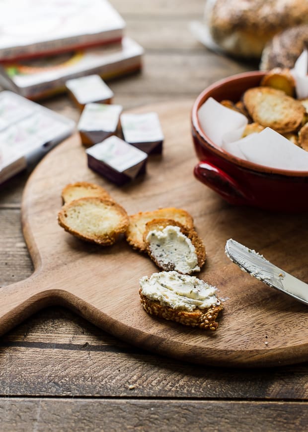 Bagel Chips spread with cheese on a wooden serving board.