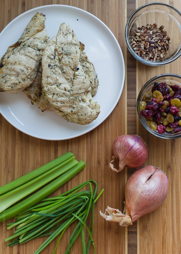 Leftover grilled chicken, celery, pecans, chives and shallots on a wooden prep surface.