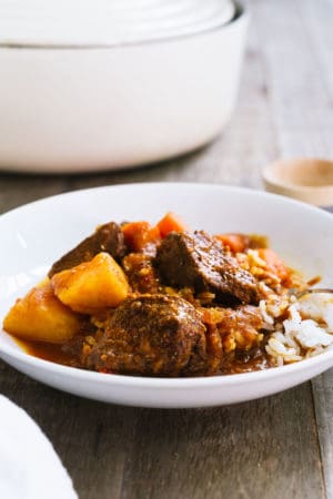 Mechado, a Filipino Beef Stew, served over a bed of rice in a white bowl.
