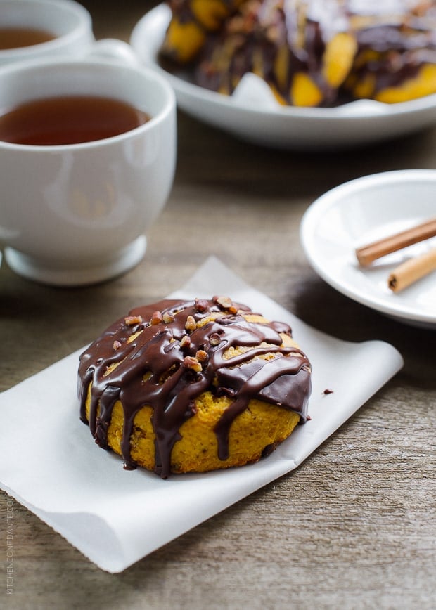 Pumpkin Cornmeal Scones drizzled with chocolate with a hot cup of tea alongside.