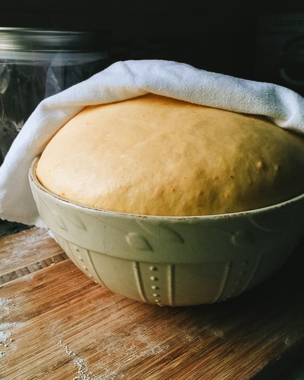 Sweet Potato Challah covered with a towel and rising in a bowl