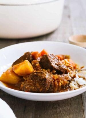 Mechado, a Filipino Beef Stew, served over a bed of rice in a white bowl.