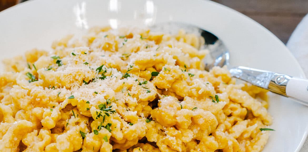 Brown Butter Pumpkin Spaetzle in a white dish garnished with finely chopped parsley.