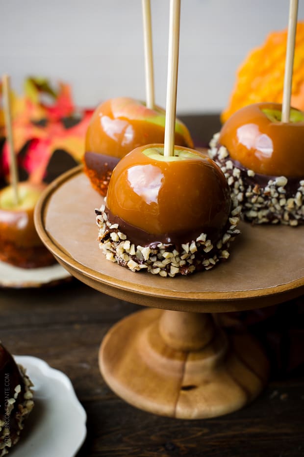 Double Dipped Caramel Apples on a wooden cake stand.