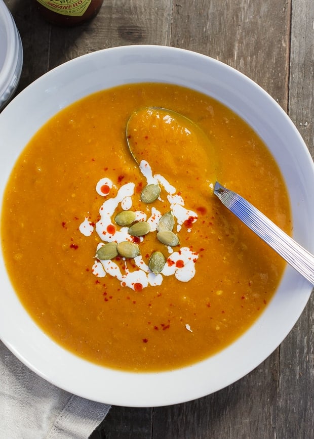 White bowl filled with Habanero Spiced Pumpkin Soup and topped with pumpkin seeds.