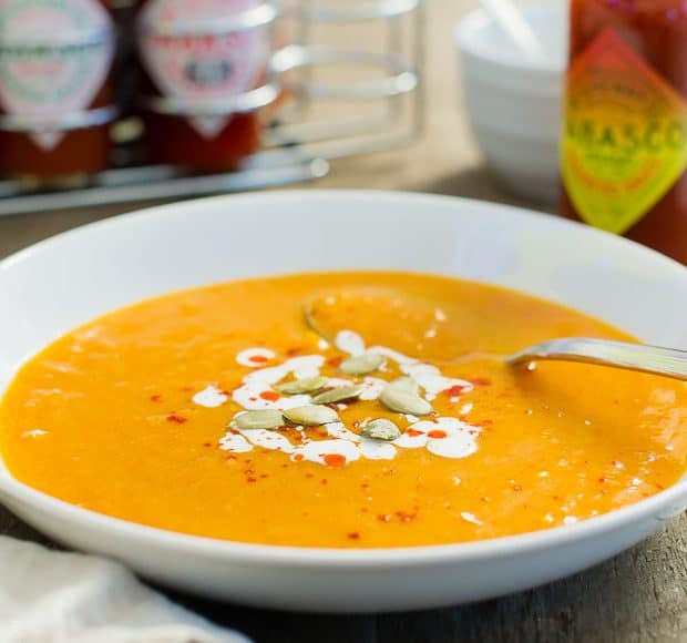 White bowl filled with Habanero Spiced Pumpkin Soup and topped with pumpkin seeds.