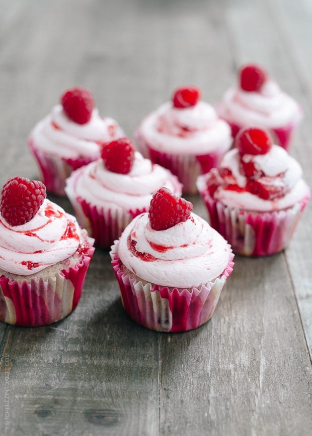 Roasted Berry Cupcakes topped with pink buttercream and a single raspberry. 