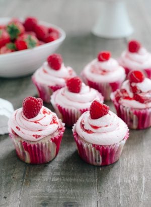 Roasted Berry Cupcakes topped with pink buttercream and a single raspberry.