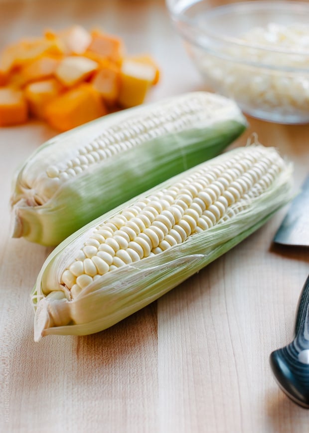 Fresh ears of corn on a counter top.
