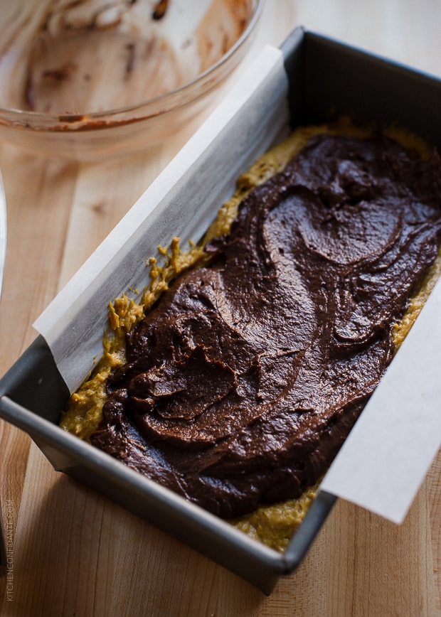 Layers of chocolate batter and pumpkin batter in a loaf pan ready to bake.