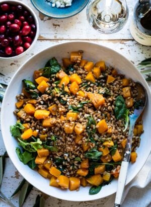 Roasted Butternut Squash Winter Salad in a white bowl on a wooden surface.