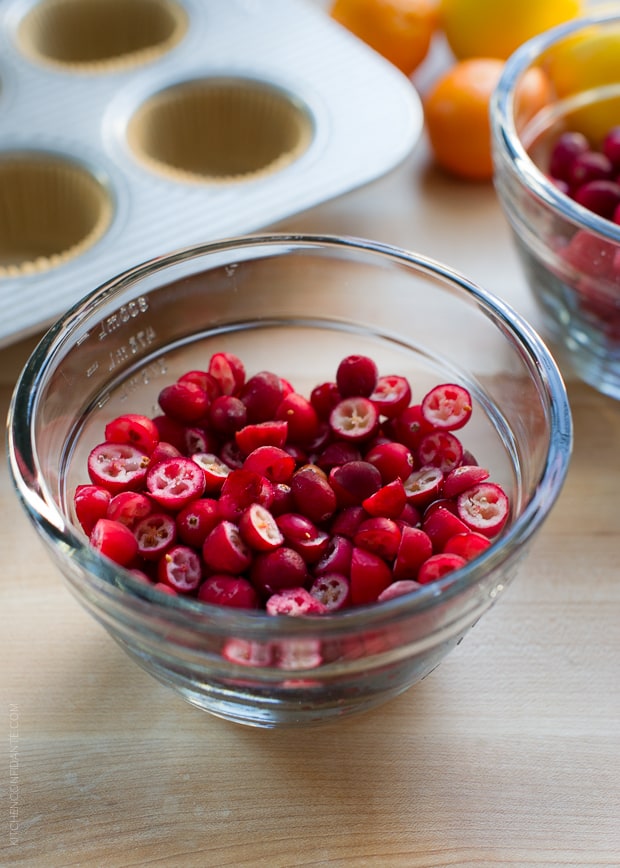 Glass bowl filled with halved fresh cranberries.