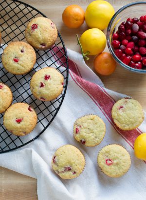 Cranberry Citrus Muffins arranged on a cooling rack and a kitchen towel, ready to eat.