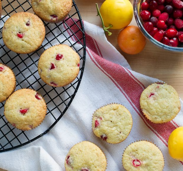 Cranberry Citrus Muffins arranged on a cooling rack and a kitchen towel, ready to eat.