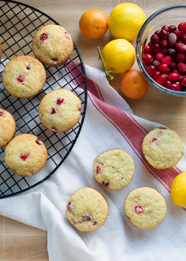 Cranberry Citrus Muffins arranged on a cooling rack and a kitchen towel, ready to eat.