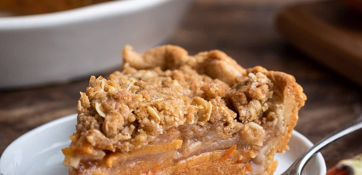 A slice of streusel topped Persimmon Apple Crumb Pie on a white plate.