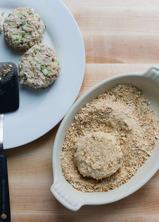 Coating crab cake sliders with crushed pretzels.