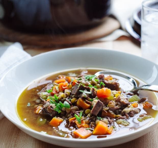 White bowl filled with Prime Rib Beef and Lentil Soup on a wooden surface.