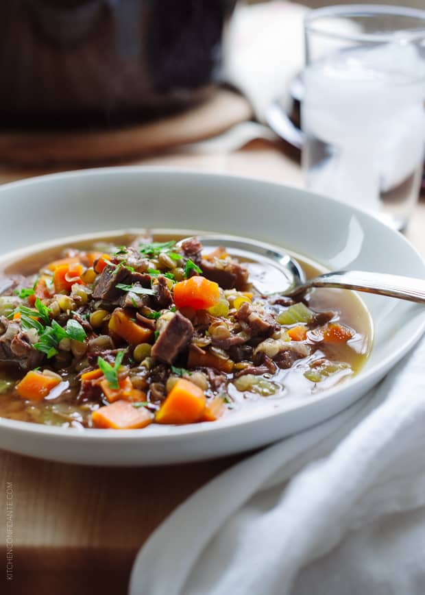 White bowl filled with Prime Rib Beef and Lentil Soup on a wooden surface.