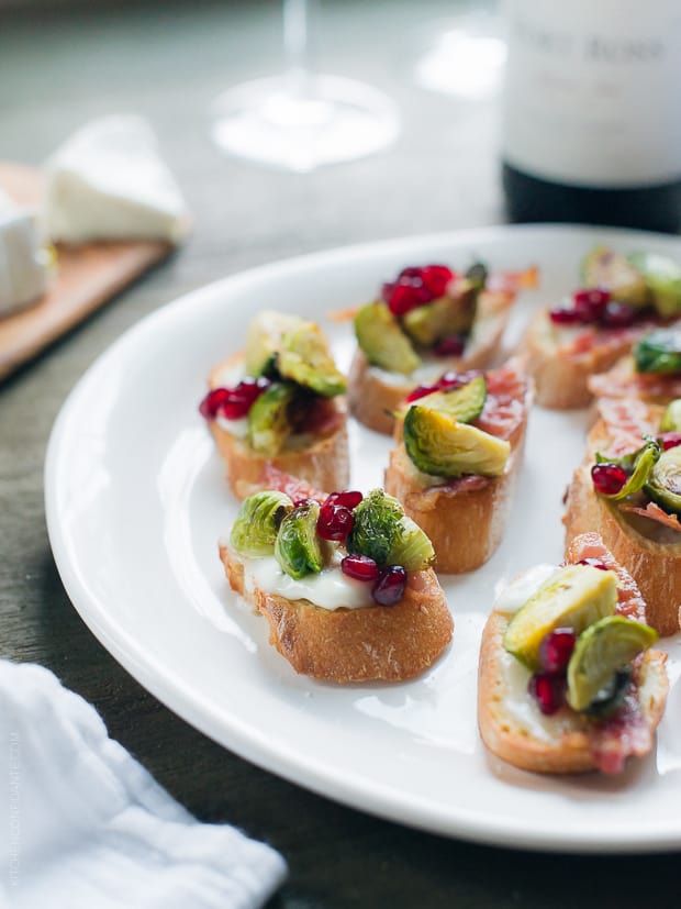 Roasted Brussels Sprouts with Bacon Crostini arranged on a white serving platter.