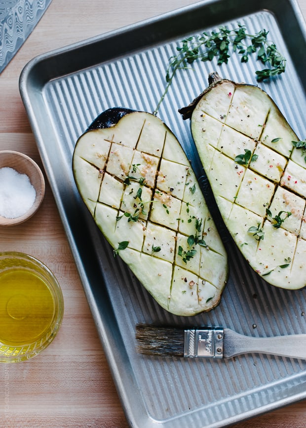 Eggplant sliced in half and placed on a baking tray.