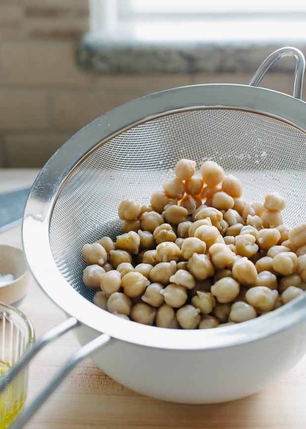 Chickpeas being rinsed in a strainer.
